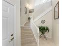Carpeted staircase with white railing, features a landing with neutral tile floors and decor at 3412 Grand Vista Ct # 202, Port Charlotte, FL 33953