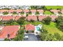 Aerial shot featuring a community pool, clubhouse, and surrounding homes with red tiled roofs at 3715 Albacete Cir # 93, Punta Gorda, FL 33950