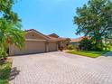 Charming home with a tile roof, three-car garage and brick paved driveway at 11982 Granite Woods Loop, Venice, FL 34292