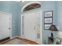 Bright foyer with a large transom window, wood floors, and sidelights around the front door at 1327 Hedgewood Cir, North Port, FL 34288