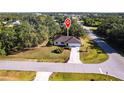 An aerial view shows the home's location on a corner lot with lush landscaping and a spacious front yard at 14534 Keene Ave, Port Charlotte, FL 33953