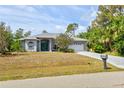 Well-maintained single-story home with a two-car garage, manicured lawn, and neutral gray exterior at 1513 Urmey Ln, North Port, FL 34286