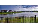 Beautiful lake view with a black fence and row of houses in the background at 16909 Caracara Pl, Punta Gorda, FL 33982