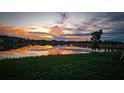 Scenic sunset reflecting on a tranquil pond surrounded by lush green grass at 16909 Caracara Pl, Punta Gorda, FL 33982