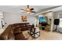 Cozy living room featuring a large sectional sofa, a ceiling fan, and a decorative stone wall with a flatscreen TV at 22498 Westchester Blvd, Punta Gorda, FL 33980