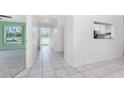 Bright hallway featuring tile flooring leading to various rooms, and view of the backyard at 25046 Doredo Dr, Punta Gorda, FL 33955