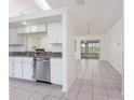 Open kitchen layout showcasing a stainless steel dishwasher, granite countertops and neutral tile flooring at 25046 Doredo Dr, Punta Gorda, FL 33955