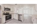 Modern kitchen featuring stainless steel appliances, granite countertops, white cabinets, and durable gray floors at 27456 Corinthian Dr, Punta Gorda, FL 33955