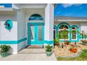 Close-up of the home's entryway, featuring a bright turquoise front door and decorative landscaping at 3027 Ridgewood Dr, North Port, FL 34287