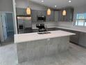 Bright kitchen features gray cabinets, quartz countertops, stainless appliances, and center island with sink at 3560 Elias Cir, North Port, FL 34288