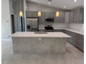 Bright kitchen features gray cabinets, quartz countertops, stainless appliances, and center island with sink at 3560 Elias Cir, North Port, FL 34288