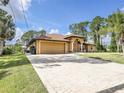 Beige one-story home featuring a long paver driveway leading to a front-facing two car garage at 8377 Mambo Ave, North Port, FL 34291