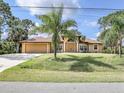 Charming one-story home with manicured lawn, mature palm trees, and a grand arched entryway at 8377 Mambo Ave, North Port, FL 34291