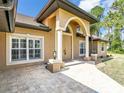 Close-up of the beige home's front entrance, showcasing the elegant archway and paver walkway at 8377 Mambo Ave, North Port, FL 34291