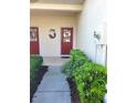 Charming front entrance with red door and decorative wreath, framed by lush landscaping at 1271 Jonah Dr, North Port, FL 34289