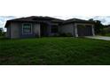 Charming one-story home with lush green lawn, gray stucco exterior, and arched front entry at 1480 Wise Dr, North Port, FL 34286