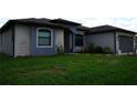Charming one-story home with blue accents, lush green lawn, and arched front entry at 1480 Wise Dr, North Port, FL 34286