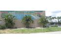 Community mural of a pool, palm trees, and cabanas with a grassy patch and fence in front at 150 Harborside Ave # 124, Punta Gorda, FL 33950