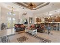 An open-concept living room features a decorative ceiling, tile floors, leather sofas, and stylish furnishings at 18602 Ashcroft Cir, Port Charlotte, FL 33948
