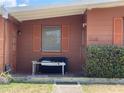 Covered porch and seating area at home's entry with shrubbery landscaping and updated paint at 2328 Picnic St, Port Charlotte, FL 33952