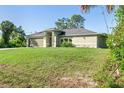Inviting single-story home with lush lawn, well manicured landscaping, and attached two-car garage at 2381 Sheila Ln, North Port, FL 34286