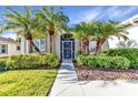 Beautifully landscaped front entrance with a stylish screen door, lush plants, and green grass at 24371 Folkstone Ave, Punta Gorda, FL 33980