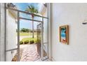 View of a tiled entryway with a decorative painting, open metal gate and landscaping at 26089 Seminole Lakes Blvd, Punta Gorda, FL 33955