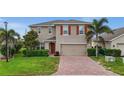 Charming two-story home with red shutters, a brick driveway, and a well-manicured lawn at 3941 River Bank Way, Punta Gorda, FL 33980
