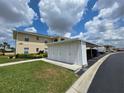 Exterior view showcasing a two-story condo, storage, covered parking, and well-manicured lawn at 5800 Sabal Trace Dr # 1201, North Port, FL 34287