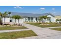 Attractive single-story home with a metal roof and landscaped front yard with palm trees and a concrete driveway at 6286 Coniston St, Port Charlotte, FL 33981