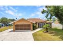 Charming single-story home with well-manicured lawn, attached garage, and security gate at entry under a clear blue sky at 78 Zenith St, Port Charlotte, FL 33954