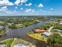 An aerial view of a waterfront home with a pool and lush landscaping, nestled in a serene coastal community at 13284 Amaryllis Cir, Port Charlotte, FL 33981