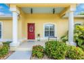 Charming home entrance featuring a red door, decorative shrubbery, and classic architectural details at 13325 Ketridge Ave, Port Charlotte, FL 33953