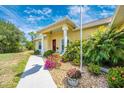 Charming yellow home featuring a landscaped yard, walkway, and inviting front entry with columns at 13325 Ketridge Ave, Port Charlotte, FL 33953