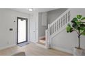 Bright entryway showcasing light wood flooring, stairs with white banister, and decorative potted plant at 17304 Vagabond Cir, Punta Gorda, FL 33955