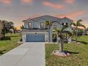 Beautiful two story home featuring a light blue garage door, stucco exterior and mature tropical landscaping at 17304 Vagabond Cir, Punta Gorda, FL 33955