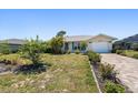 Well-manicured front yard with a paver driveway leading to a charming home with turquoise accents at 25449 Doredo Dr, Punta Gorda, FL 33955