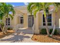Charming home entrance featuring decorative glass door, columns, and tropical landscaping at 2719 Mayaguana Ct, Punta Gorda, FL 33950