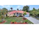 Charming single-Gathering home with a red roof, well-kept lawn, and tropical landscaping at 3058 Curry Ter, Port Charlotte, FL 33981
