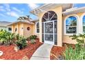 Close-up of the front entrance with decorative door, arched windows and mulch landscaping at 3058 Curry Ter, Port Charlotte, FL 33981