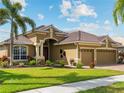 Beautiful home featuring a well-manicured lawn, mature landscaping, and a three-car garage at 5461 White Ibis Dr, North Port, FL 34287