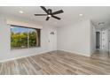Sunlit living room boasts wood-look floors, ceiling fan, and access to hallway at 4282 Pocatella Ave, North Port, FL 34287