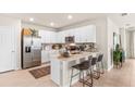 Modern kitchen with white cabinets, stainless steel appliances, and breakfast bar seating at 5028 Schubert Trl, North Port, FL 34287