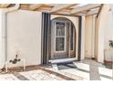 Covered front patio featuring a secure wrought iron door with an arched top, patterned tile, and garden hose at 5046 San Rocco Ct, Punta Gorda, FL 33950