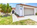 Exterior of the home featuring a two-car garage, a well-manicured lawn, and a pathway to the arched entrance at 5046 San Rocco Ct, Punta Gorda, FL 33950
