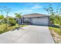 Single-story home with a spacious driveway and attached garage with lush landscaping at 9295 Melody Cir, Port Charlotte, FL 33981