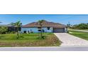 A well-maintained home featuring a brick driveway and an attached garage with lush landscaping at 10233 St Paul Dr, Port Charlotte, FL 33981