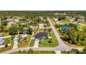 Aerial view of a cozy home with a large yard and screened-in pool, nestled in a lush, green neighborhood under a clear blue sky at 1321 Calgary Rd, North Port, FL 34288