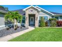 Inviting entryway with stone accents and manicured landscaping featuring a paved walkway to a white front door with decorative glass at 1321 Calgary Rd, North Port, FL 34288