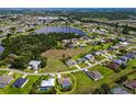 Aerial view of house featuring an in-ground pool surrounded by palm trees near a peaceful, blue lake at 1612 Blue Lake Cir, Punta Gorda, FL 33983